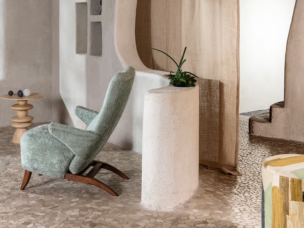 Ein grüner Sessel, ein brauner Vorhang und ein gemusterter Pouf.