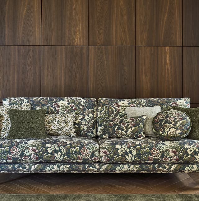Eine Aufnahme von einem gemusterten Sofa in einem dunklen, holzverkleideten Raum. 