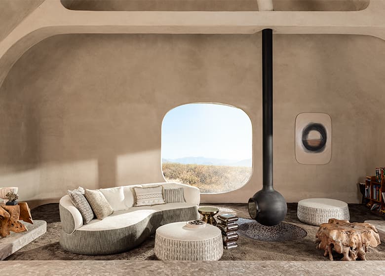 Graues Sofa mit grauen Kissen und 2 grauen Poufs.