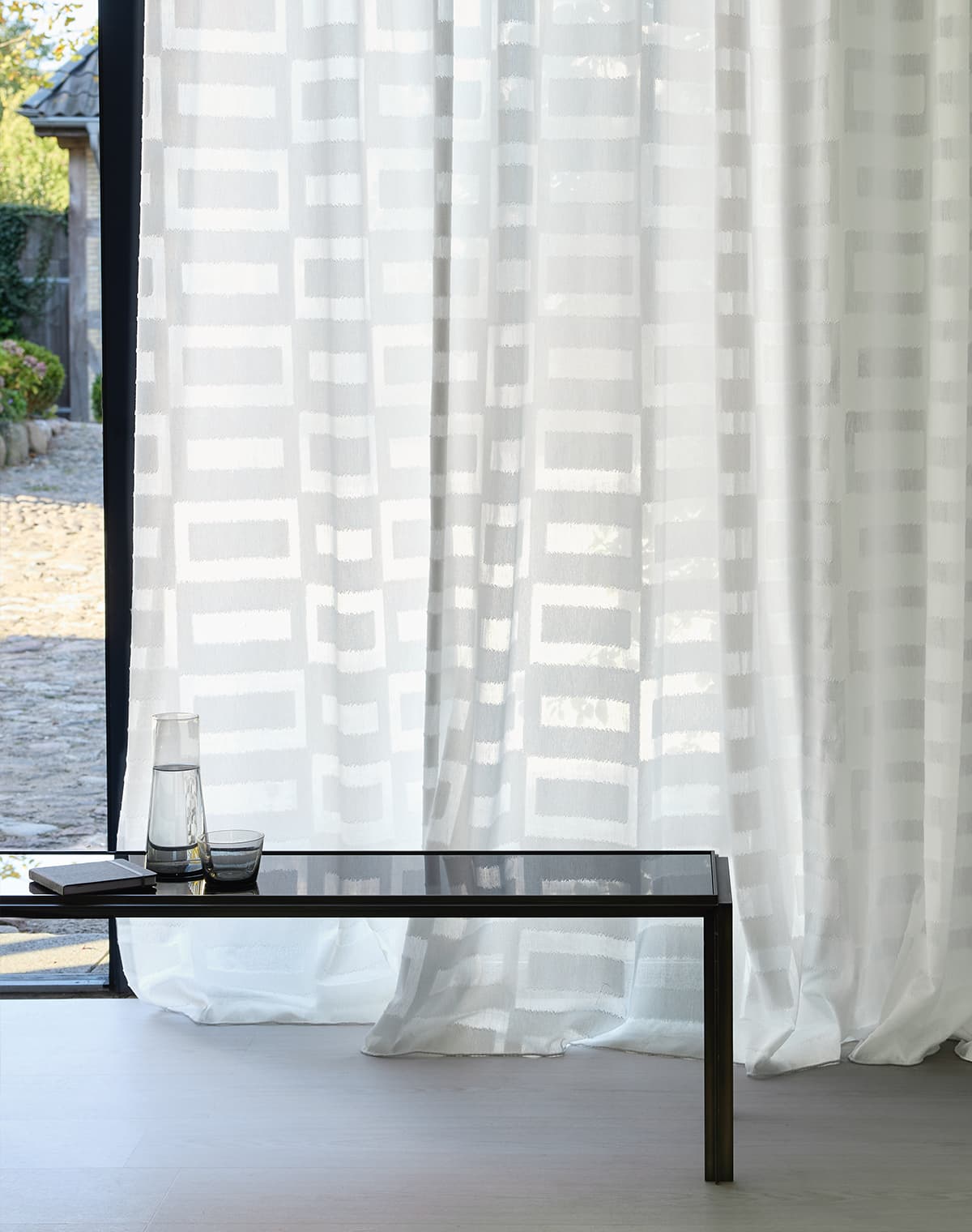 Transparente Gardine mit Muster am Terrassenfenster.