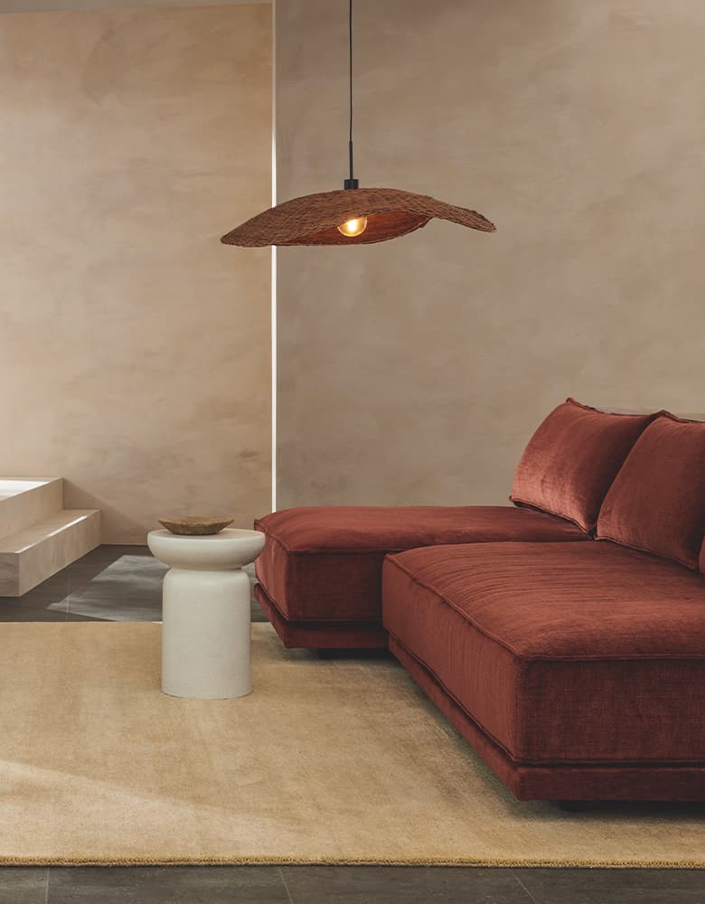 Eine Aufnahme von einem rostbraunen Sofa auf einem beigen Teppich.