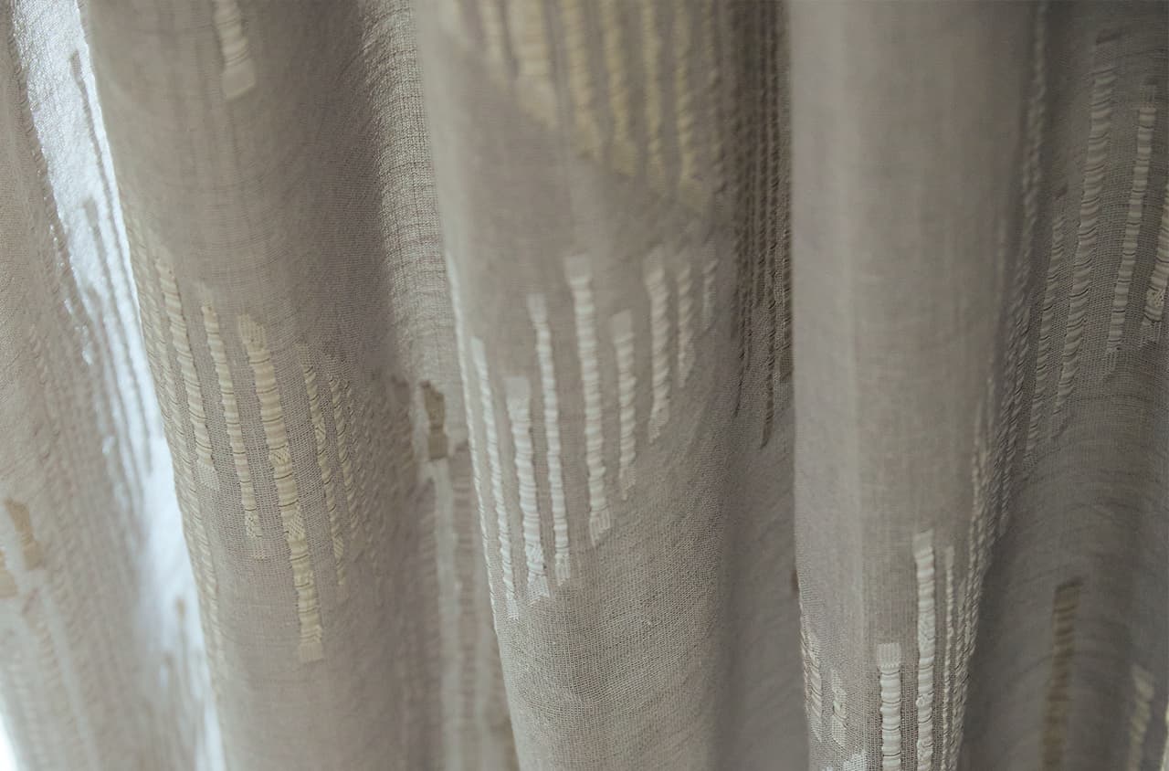 Beige Gardine mit goldenem grafischem Muster.