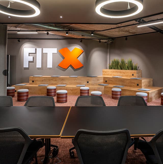 Eine Aufnahme von einem großen Konferenztisch in der Mitte, im Hintergrund sieht man eine Sitzbanksituation.