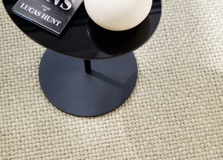 Beigefarbiger Teppich  auf dem ein kleiner Tisch steht Detailbild