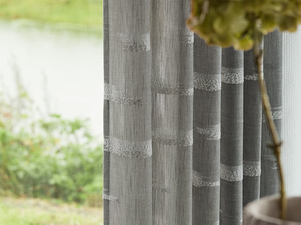 Grau-weiße Gardine am Fenster