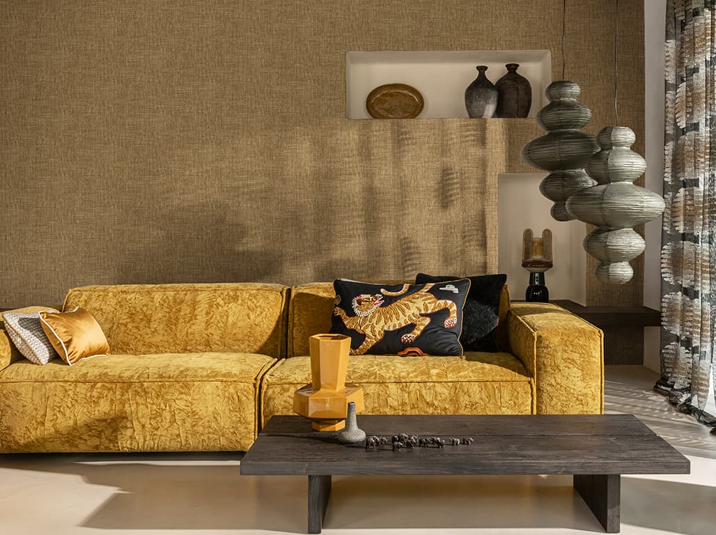 Goldenes Sofa, ein Kissen mit Tiger-Stickerei, ein Holztisch und eine braune Tapete