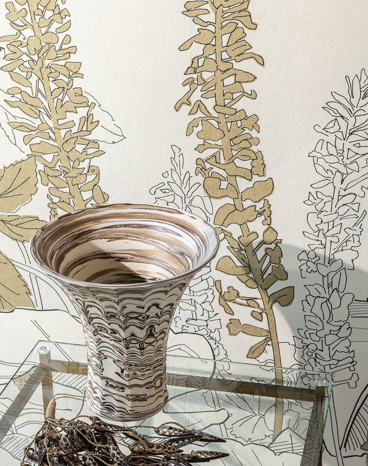 Weiße Tapete mit floralem Muster und eine Vase auf einem Glasbeistelltisch