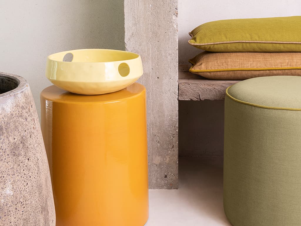 Das Bild zeigt Poufs und Kissen in Orange und Grün. Die verschiedenen Elemente bringen eine Vielzahl von Farben in unterschiedlichen Tönen ins Bild und schaffen eine lebendige Atmosphäre.