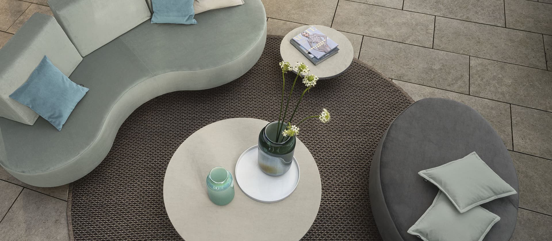 Outdoor-Lounge mit einem dunkelgrauen Teppich und blauen Sitzmöbeln