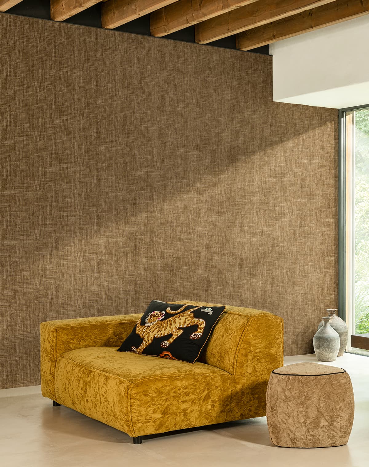 Goldenes Sofa, ein Kissen mit Tiger-Stickerei, brauner Pouf und eine braune Tapete