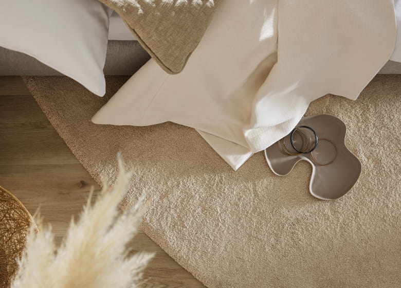 Heller runder Teppich liegt unter einem Bett.
