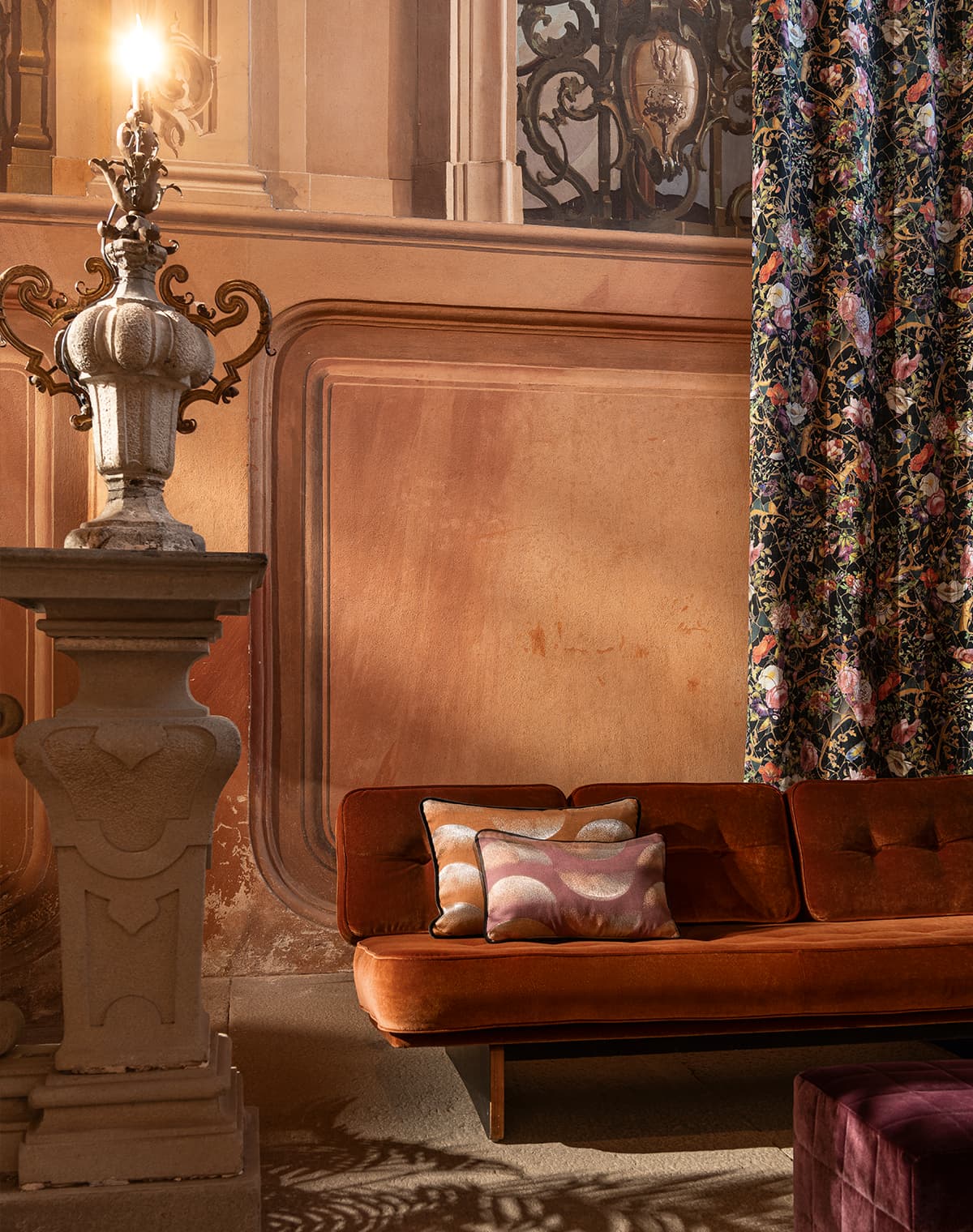 Rotes Sofa mit Kissen und ein Vorhang mit floralem Print