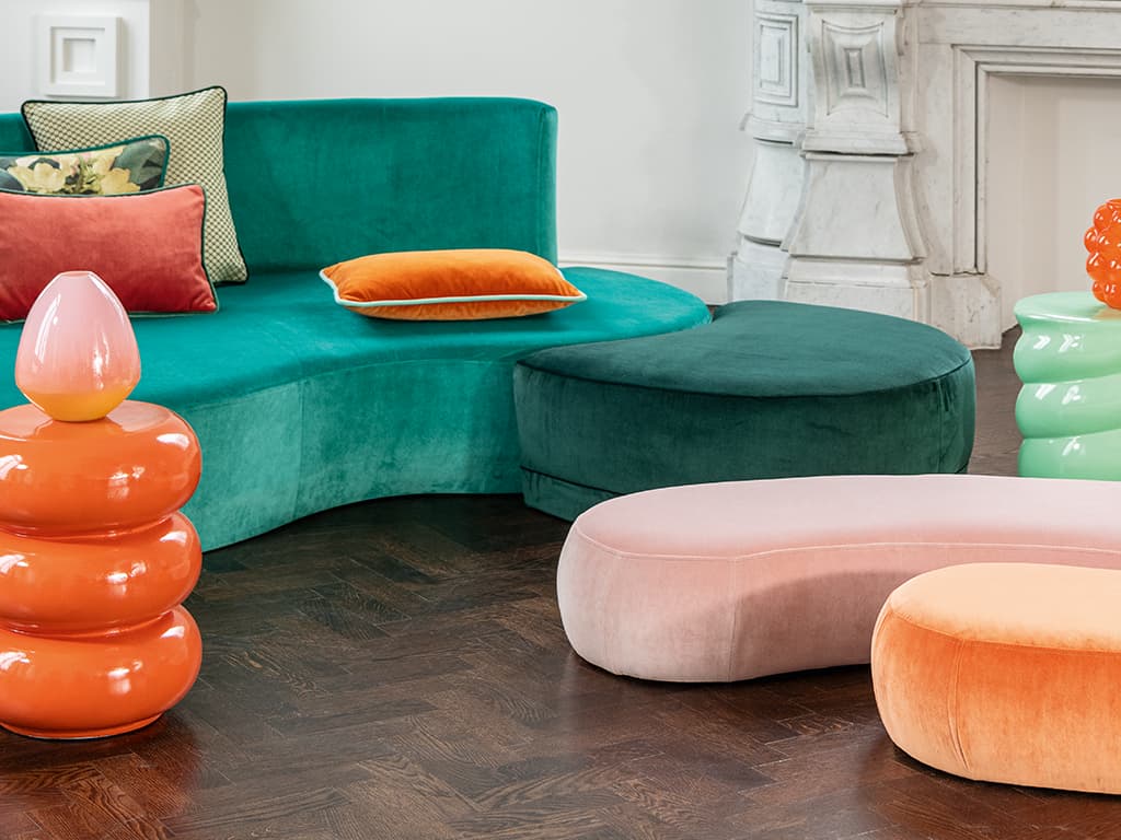 Ein grünes Sofa und zwei Poufs in rosa und orange.