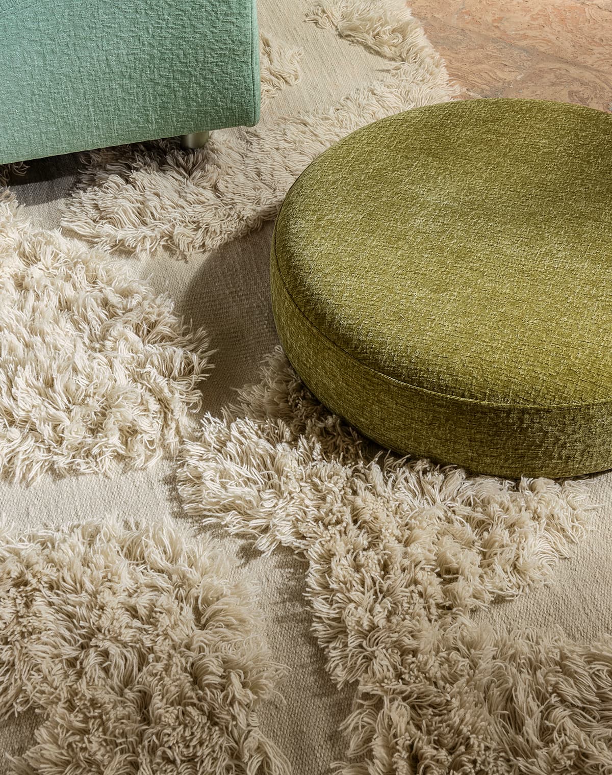 Ein weißer, flauschiger Teppich und ein grüner Pouf