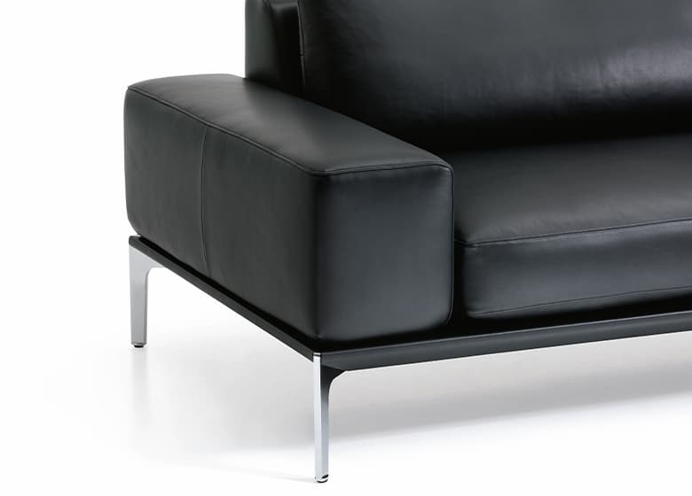 Nahaufnahme einer schwarzen breiten Armlehne eines Ledersofas.