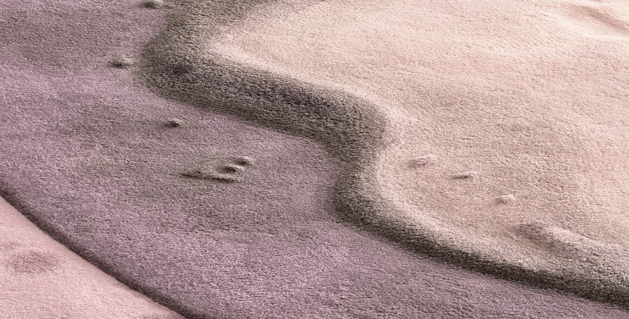 Nahaufnahme von einem Teppich der von eienm rosa optisch wie eine Flüssigkeit in einen andere rosanen Ton übergeht