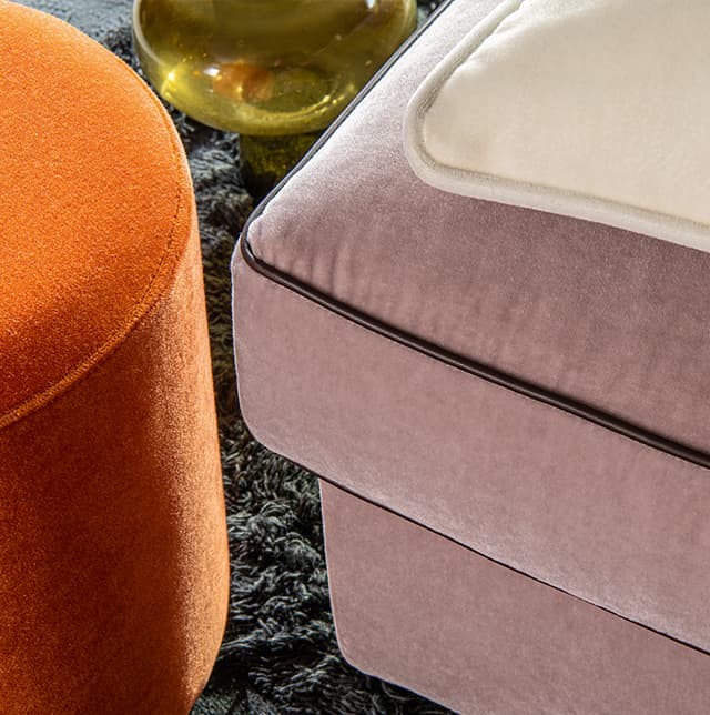 Orangener Pouf und ein Sofa in rosa