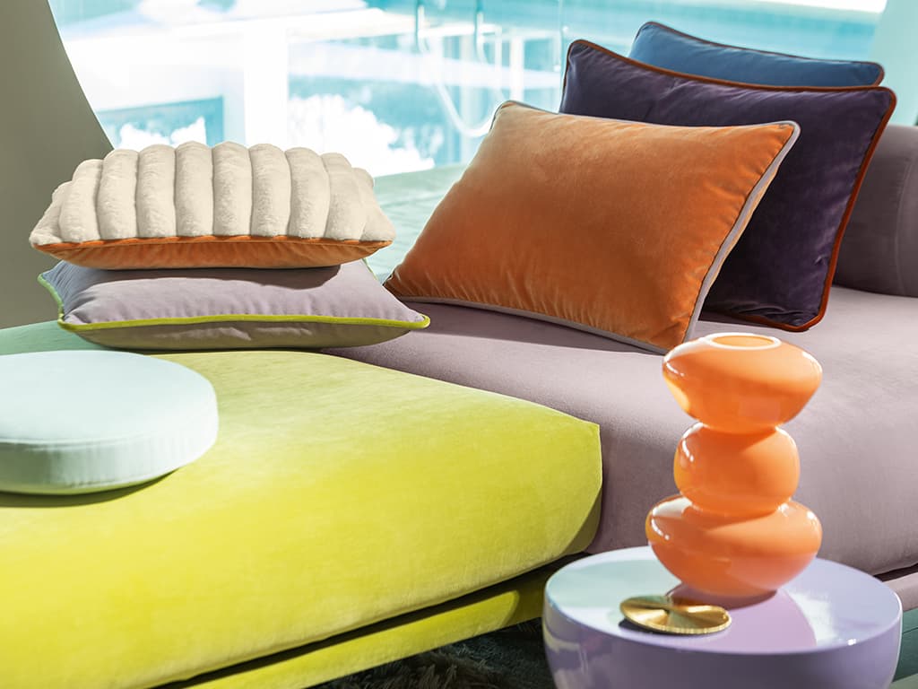 Bunte Kissen auf einem zweifarbigen Sofa in gelb und rosa.