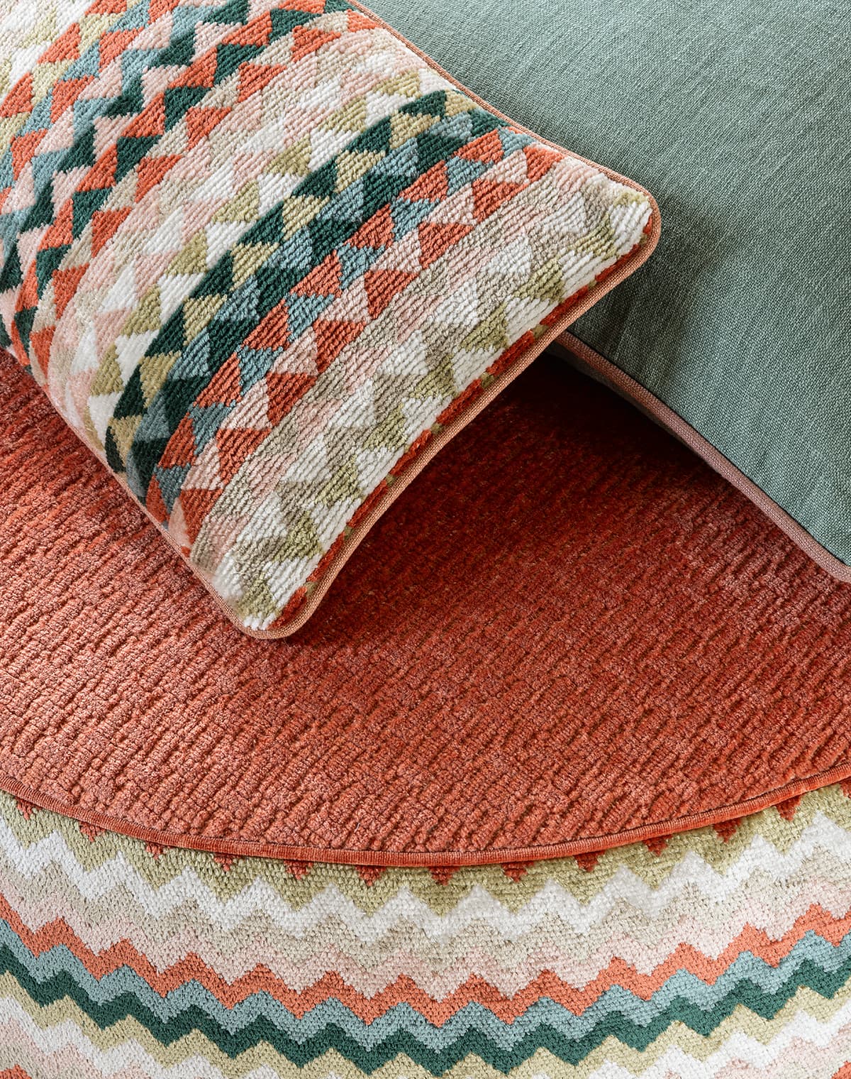 Ein Kissen und ein Pouf mit buntem, grafischem Zick-Zack-Muster.