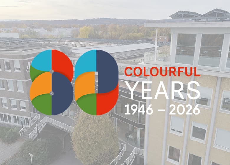 Eine Aufnahme von dem Headquarter in Bielefeld im Hintergrund und das Jubiläumslogo im Vordergrund.