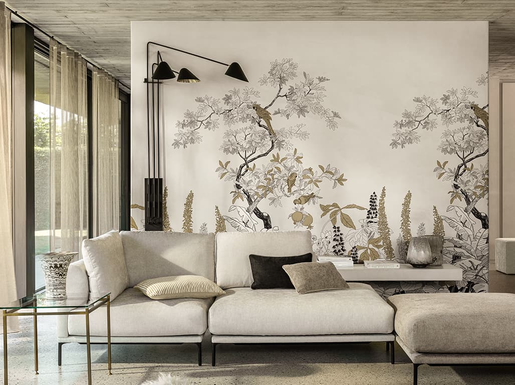 Weißes Sofa mit Kissen vor einer weißen Tapete mit floralem Printmotiv